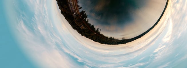 Fisheye – A unique aerial shot of a serene lake beside a road, distorted into a stunning fisheye perspective.