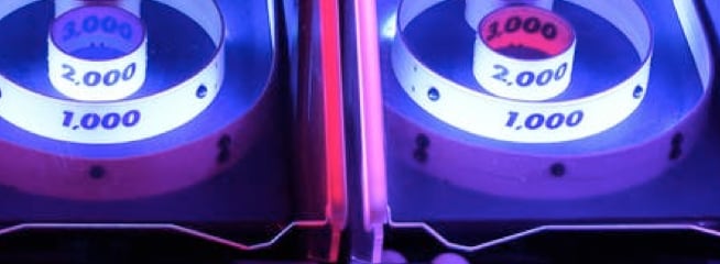 Night Arcade – A neon-lit arcade featuring an interactive game where players aim and hit balls at illuminated targets, creating an energetic atmosphere.